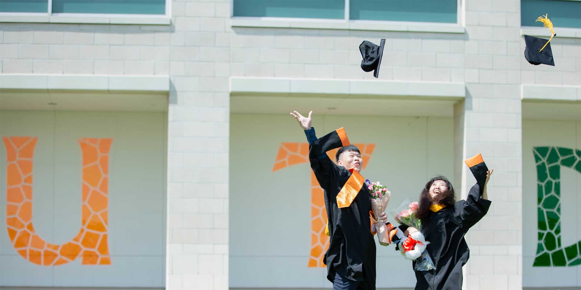 A master's degree in business administration graduate and a master's degree in supply chain management graduate celebrating on commencement day.